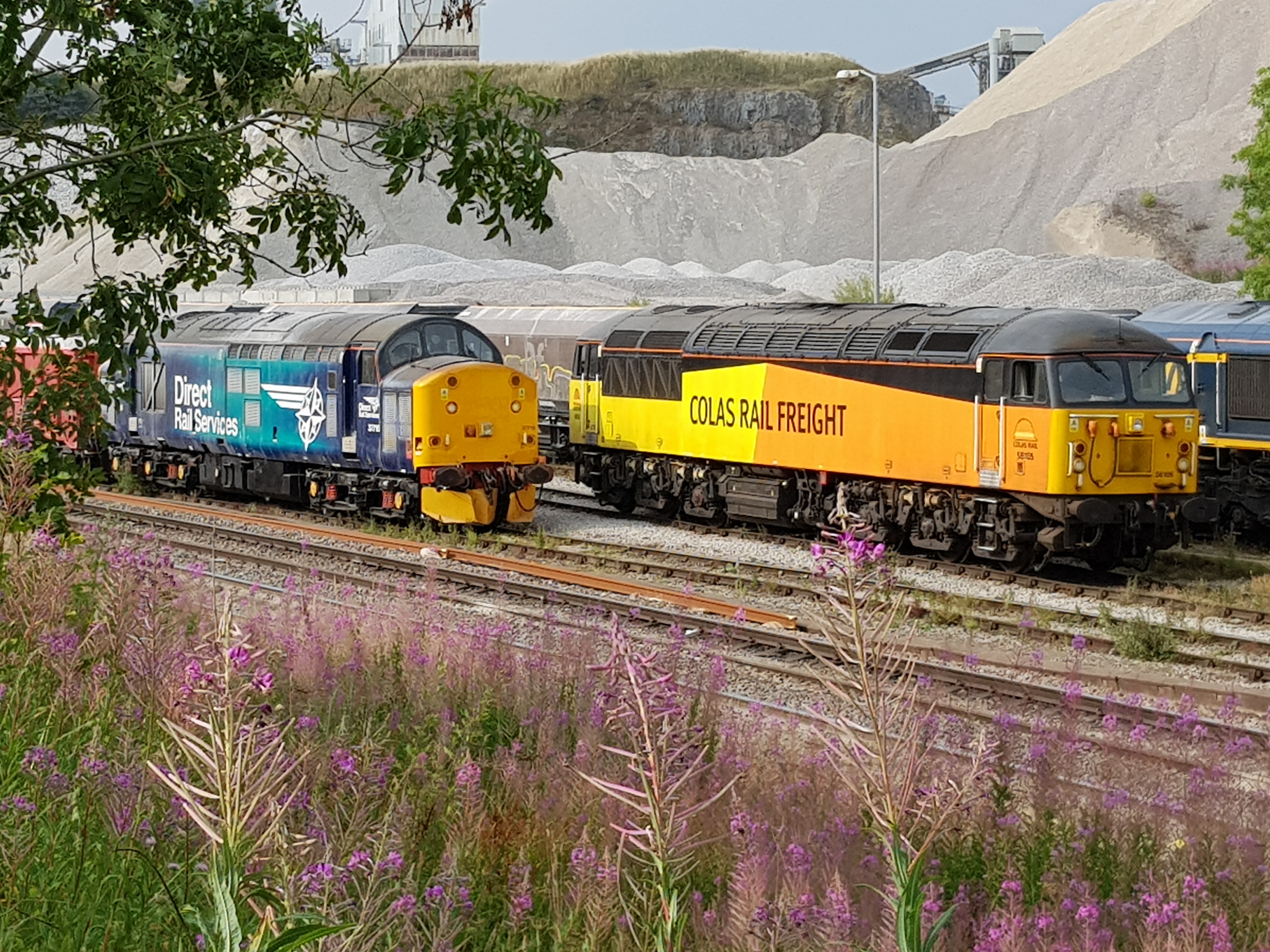 Latest Victa Rail / GBRf hire-in loco 56105 stands at Peak Forest alongside fellow hire-in 37716 on 28th July 2018. Photo copyright: Keith Bulmer.