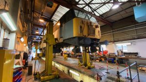 56301 is seen up on the jacks during work to replace the worn wheelsets with a set from under 56007.